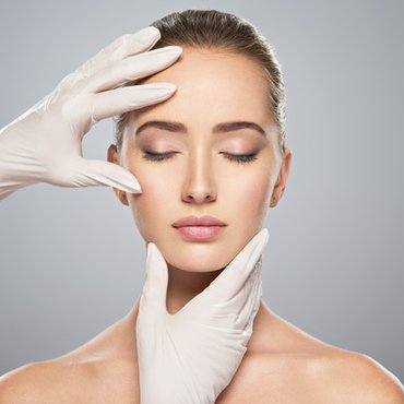 Hands framing a woman's face to highlight aesthetic treatments